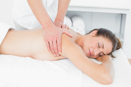 Close-up of male physiotherapist massaging woman's back in the medical officeの写真素材