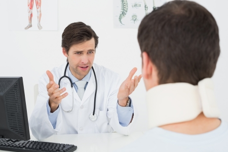 Male doctor in conversation with patient at desk in medical officeの写真素材
