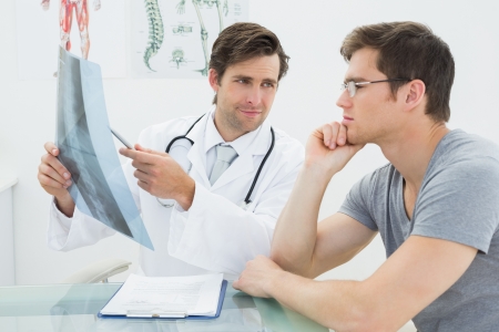 Male doctor explaining spine x-ray to patient in the medical officeの写真素材