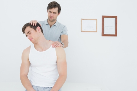 Male chiropractor doing neck adjustment in the medical officeの写真素材