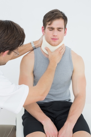 Male doctor examining a patients neck in the medical officeの写真素材