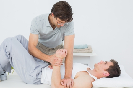 Male physiotherapist examining a young mans hand in the medical office