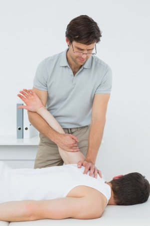 Male physiotherapist examining a young mans hand in the medical officeの写真素材