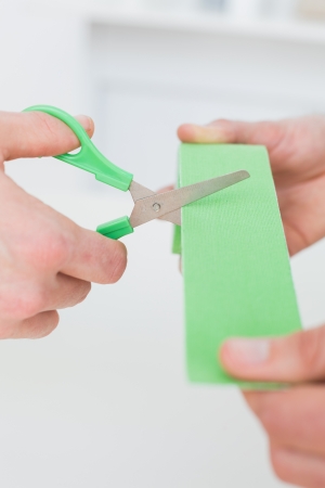 Extreme close-up of hands holding kinesio tape and scissors over white backgroundの写真素材