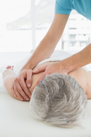 Close-up of a physiotherapist massaging a senior woman's back in the medical officeの写真素材
