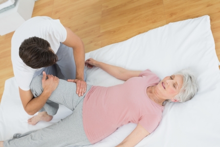 High angle view of a physical therapist examining senior woman's leg at the hospital gymの写真素材