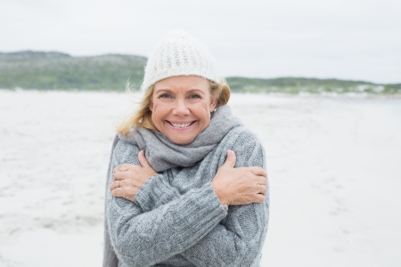 Portrait of a happy senior woman feeling cold at the beachの写真素材