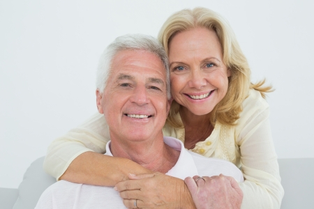 Portrait of a happy senior woman embracing man from behind at homeの写真素材