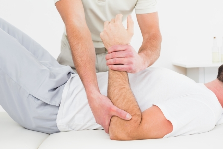 Mid section of a male physiotherapist examining a young man's hand in the medical officeの写真素材