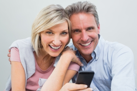 Close-up portrait of a cheerful casual couple with mobile phoneの写真素材
