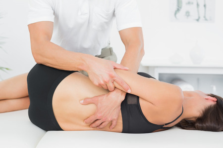Male physiotherapist massaging woman's back in the medical officeの写真素材