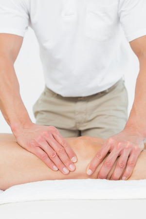 Extreme close-up of a male physiotherapist examining a young woman's leg in the medical officeの写真素材