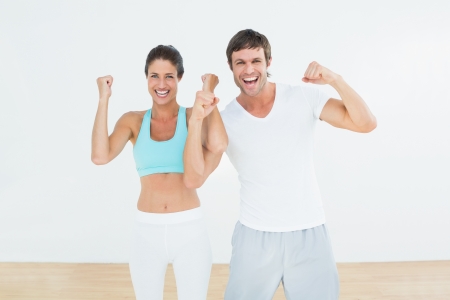 Portrait of a cheerful fit young couple clenching fists in the fitness studioの写真素材