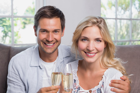 Close-up portrait of a cheerful loving young couple with champagne flutes at homeの写真素材