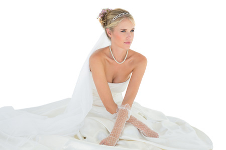 Thoughtful woman in wedding dress looking away over white backgroundの写真素材