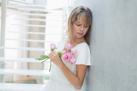 Portrait of a beautiful sad young woman with flowers at homeの写真素材