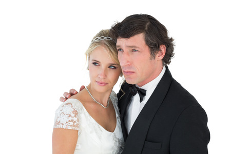 Thoughtful bride and groom looking away over white backgroundの写真素材