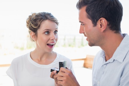 Young man surprising beautiful woman with a wedding ring at homeの写真素材