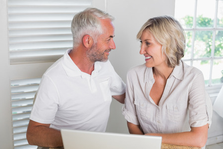 Smiling mature couple using laptop at homeの写真素材