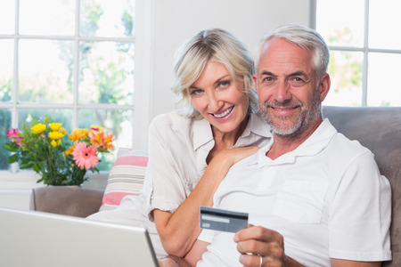 Happy mature couple doing online shopping through laptop and credit card at homeの写真素材