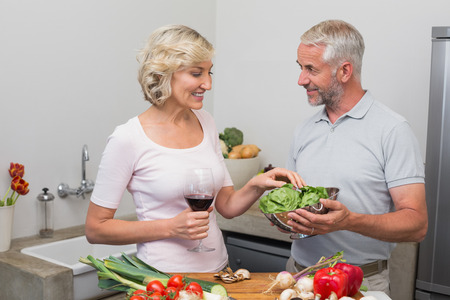 Happy mature couple preparing food together in the kitchen at homeの写真素材