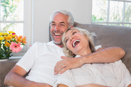 Cheerful relaxed mature couple sitting on couch at homeの写真素材
