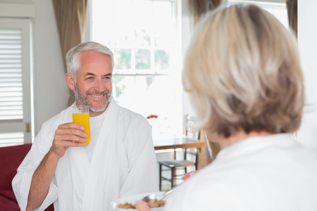 Portrait of a smiling mature man having breakfast with cropped woman at homeの写真素材