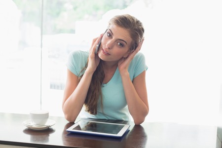 Young woman with coffee cup using digital tablet and cellphone at counter in the coffee shopの写真素材