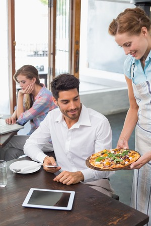 Waitress giving pizza to a smiling young man at the coffee shopの写真素材
