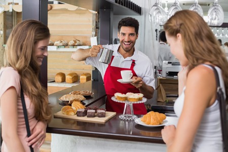 Portrait of female friends with male barista at counter in the coffee shopの写真素材