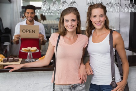 Portrait of female friends with male barista at counter in the coffee shopの写真素材