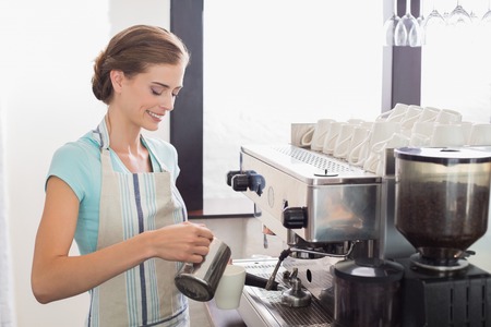 Portrait of a smiling female barista preparing espresso at coffee shopの写真素材