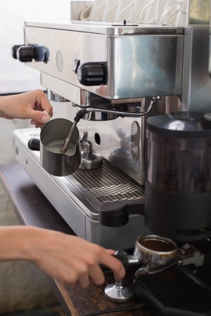 Close-up mid section of a barista prepares espresso in coffee shopの写真素材