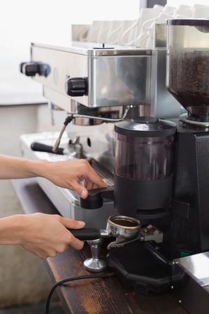 Close-up mid section of a barista prepares espresso in coffee shopの写真素材