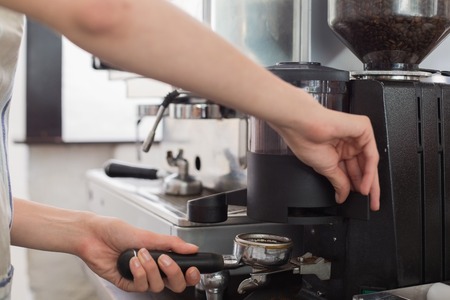Close-up mid section of a barista prepares espresso in coffee shopの写真素材