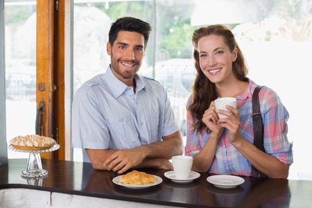Portrait of a smiling young couple with coffee and croissant at the coffee shopの写真素材