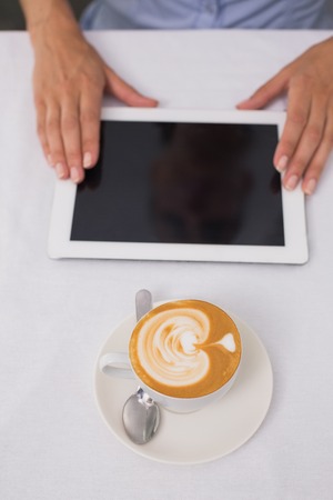 Close-up of digital tablet and coffee on table in the coffee shopの写真素材