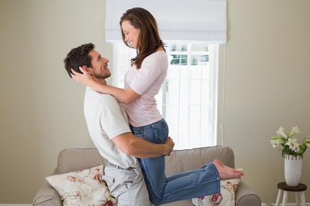 Side view of a smiling young man carrying woman at home