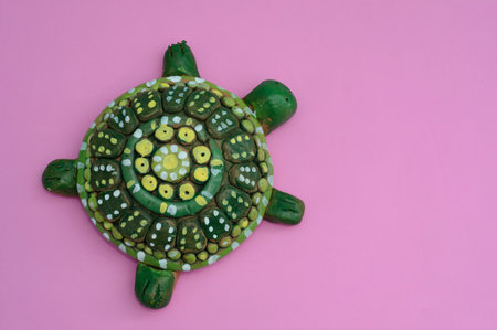 Colorful ceramic turtle on pink background, closeup of photo.