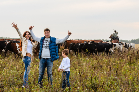Young family and a herd of cows in the backgroundの写真素材