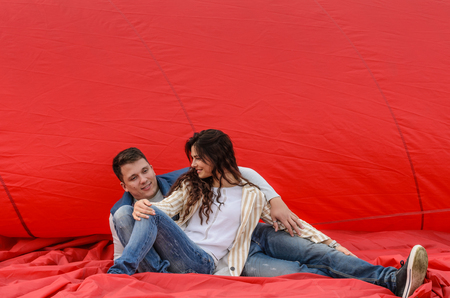 Young couple sitting on a red backgroundの写真素材