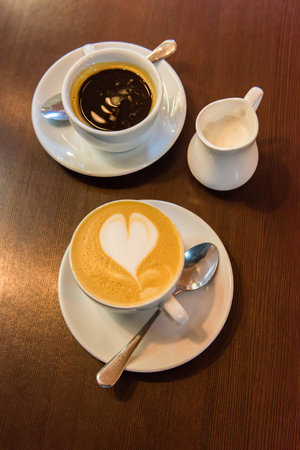 Cup of black coffee, cup of cappuccino and a milk jug