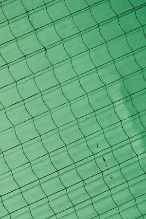 Texture of translucent frosted green glass with diagonal straight and wavy lines