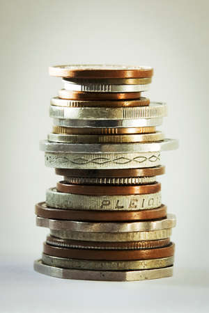 A big stack of coins from different countries with a focus on the faces of coins on a white backgroundの写真素材