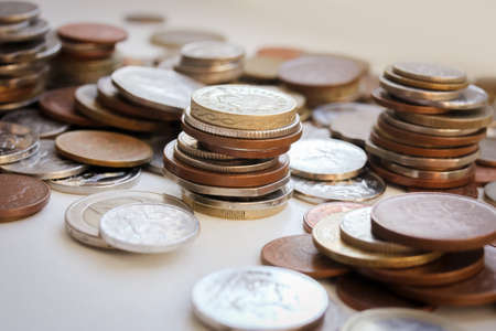 Scattered coins of different countries and stacks of coins with selective focus, side viewの写真素材