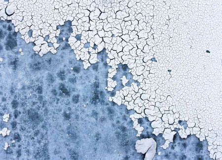 White cracked plaster on a blue wall with stains, textured wall background, cracks on the wall macroの写真素材