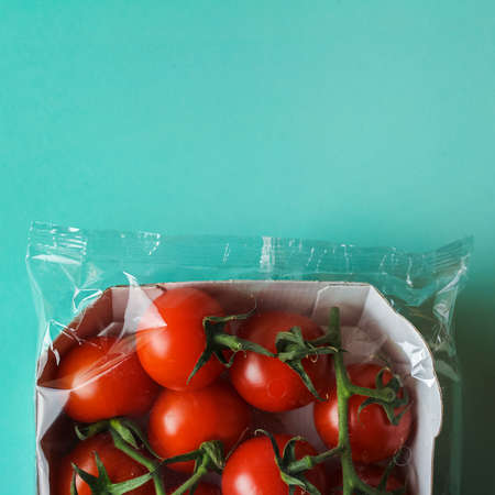 Cherry tomatoes in a transparent package on a green background, food packaging