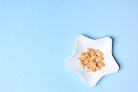 Star shaped plate with fish shaped cookies on blue background, top view, minimalist foodの写真素材