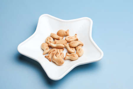 Star shaped plate with fish shaped cookies on blue background, minimalist foodの写真素材