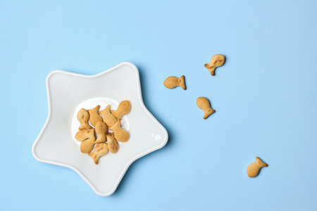 Star shaped plate with fish shaped cookies on blue background, top view, minimalist foodの写真素材